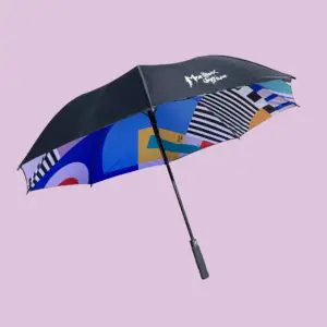 The Big Umbrella Camille Walala features a vibrant, Walala-inspired geometric-patterned underside and the Montreux Jazz Festival logo on top, shown against a plain light purple background.