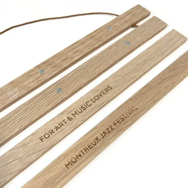Three wooden slats make up this Magnetic Engraved Poster Holder—two are engraved with FOR ART & MUSIC LOVERS and MONTREUX JAZZ FESTIVAL, and one features a string for hanging. Perfect for showcasing your favorite Montreux Festival memories.