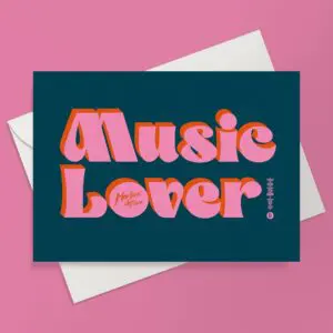 La carte de vœux "The Music Lover" présente un texte audacieux et rétro en rose et orange sur fond bleu foncé, qui fait écho à l'esprit vibrant du festival de Montreux. Elle est présentée sur une enveloppe blanche surmontée d'une surface rose.
