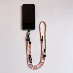 Un smartphone avec le Lakeside Mobile Strap, doté d'un design coloré Montreux Jazz et d'un clip noir, soigneusement disposé sur une surface légère.