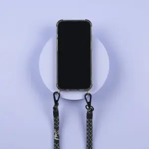 A smartphone in a clear case hangs on a light purple wall, attached to two black-and-white “Lakeside” Mobile Straps with metal clasps—perfect for showing off your style at Festival Montreux.