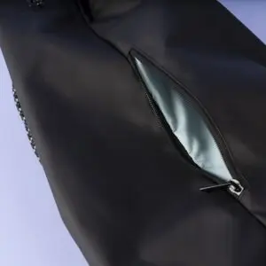 Close-up of a black zippered pocket on the Sailing Bag, Lakeside, partially unzipped to reveal a light blue interior lining. The bag is set against a light purple background and is inspired by the Montreux Festival.