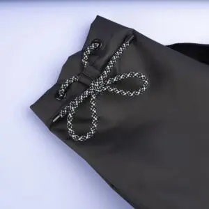 Close-up of the Sailing Bag, Lakeside, showing a black drawstring with a braided black-and-white cord tied in a bow and metal eyelets, set against a light background.