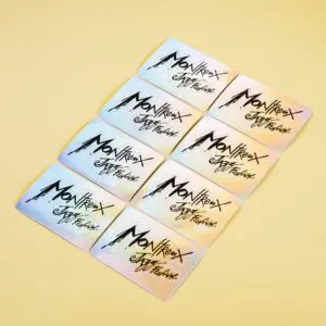 Nine pastel-colored cards are arranged in a grid on a light yellow surface, each showcasing the Holographic Sticker Montreux Jazz Festival with bold artistic lettering and a stylized mountain graphic.