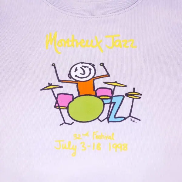 White graphic sweatshirt for kids features “Montreux Jazz” in yellow above a stick figure playing colorful drums. Below, “32nd Festival July 3-18 1998” appears in yellow—Phil Collins performed that year.