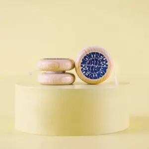 Trois Yoyo Vintage Montreux Jazz en bois avec texte bleu reposent sur un socle rond jaune pâle, deux empilés et un debout pour montrer son design unique, le tout sur un fond assorti.