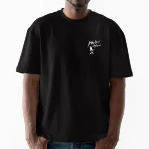 Une personne se tient debout sur un fond blanc uni et porte le t-shirt Lineup 2024 en édition limitée, avec une coupe ample noire, un petit graphique blanc et le texte "Monlixx Costume" sur la poitrine gauche, de la collection Festival Montreux.