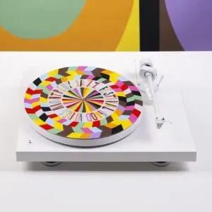 MJF25-Shooting-Lakwena-slipmat-3.jpg The Slipmat Vinyl Lakwena is a white turntable slipmat with a colorful geometric pattern and the words "Montreux Jazz Festival Good Vibes," set against a vibrant, abstract background.